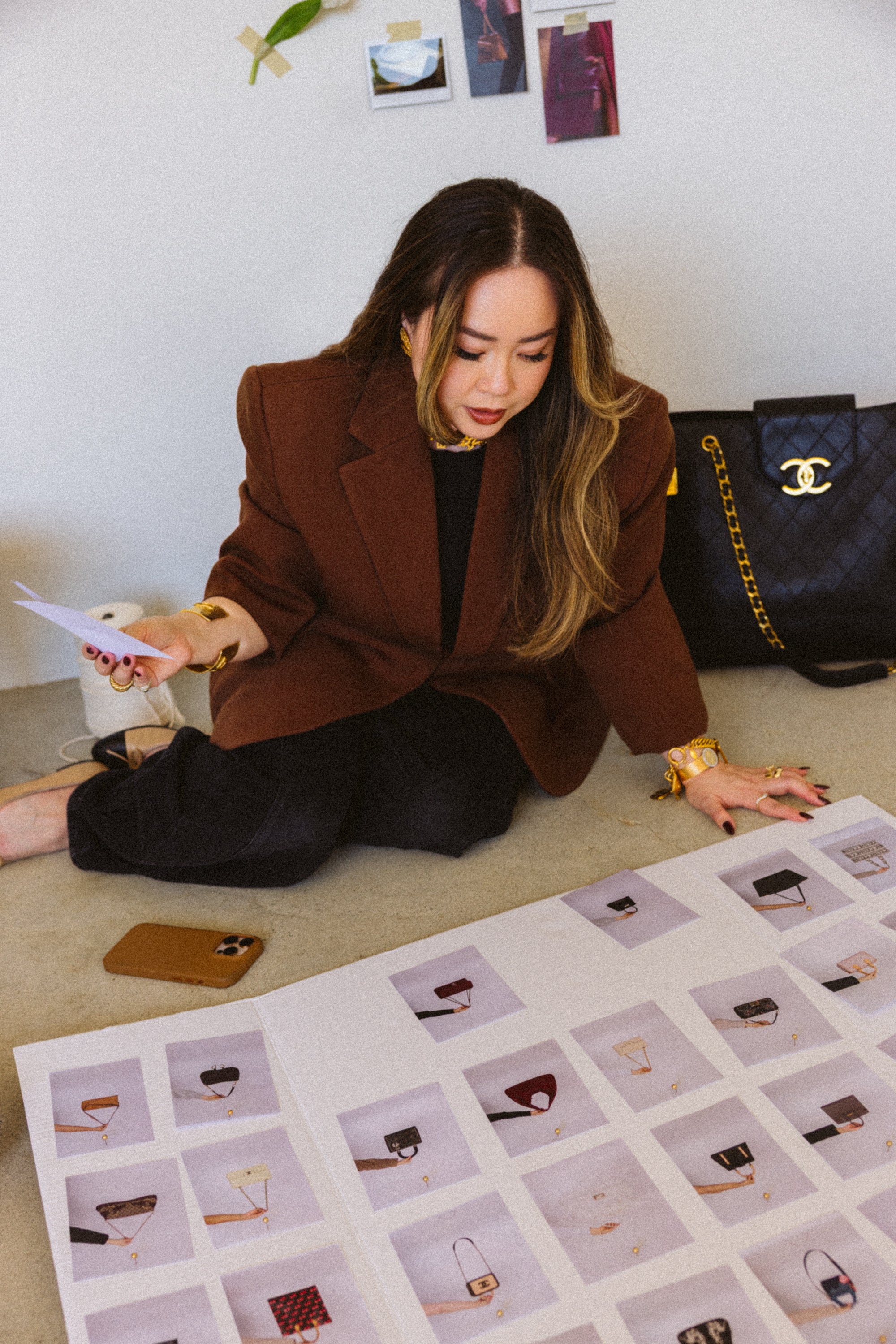 Woman sitting on the floor looking at a grid of images with bags and shoes.