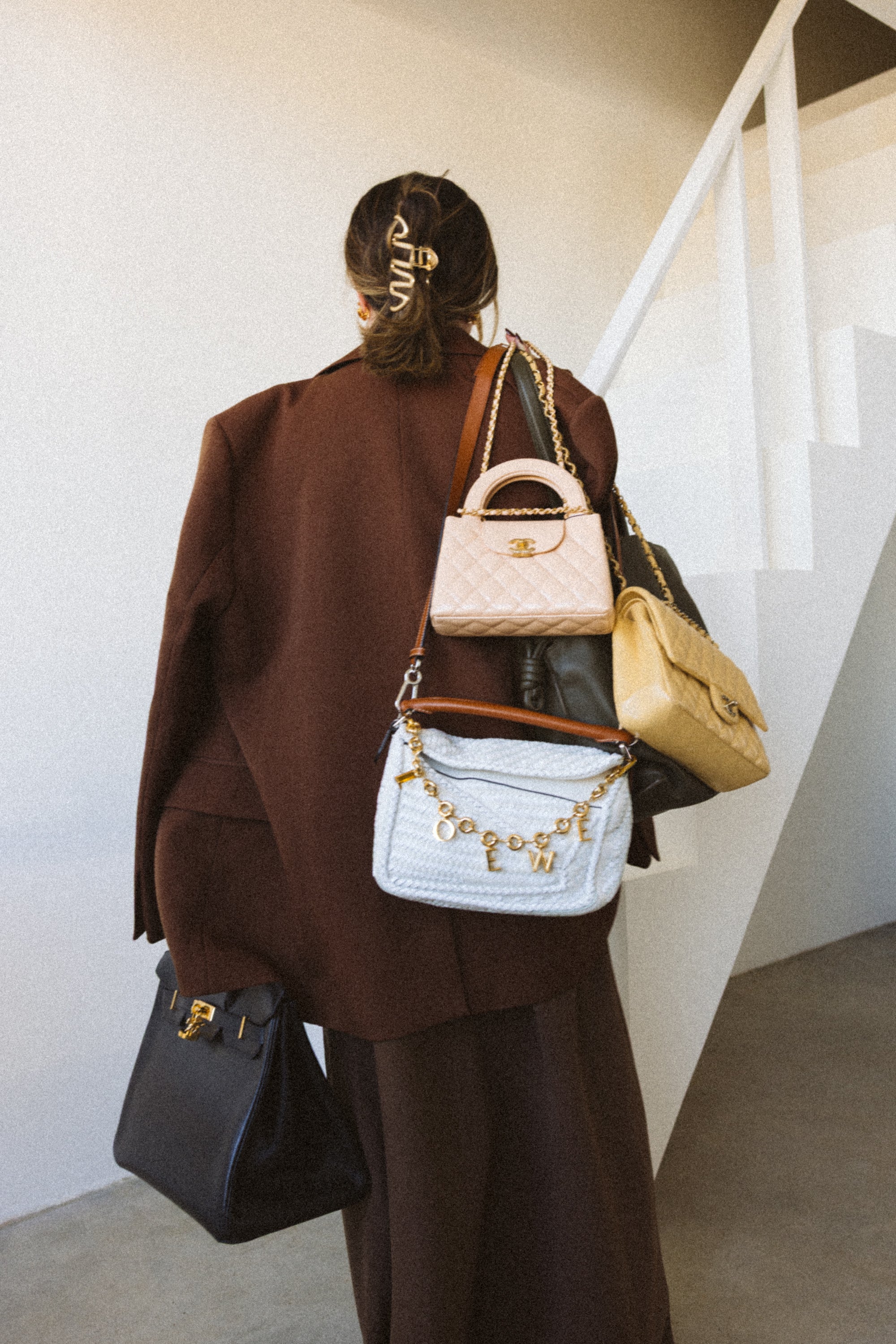 Person wearing multiple handbags in a minimal indoor setting