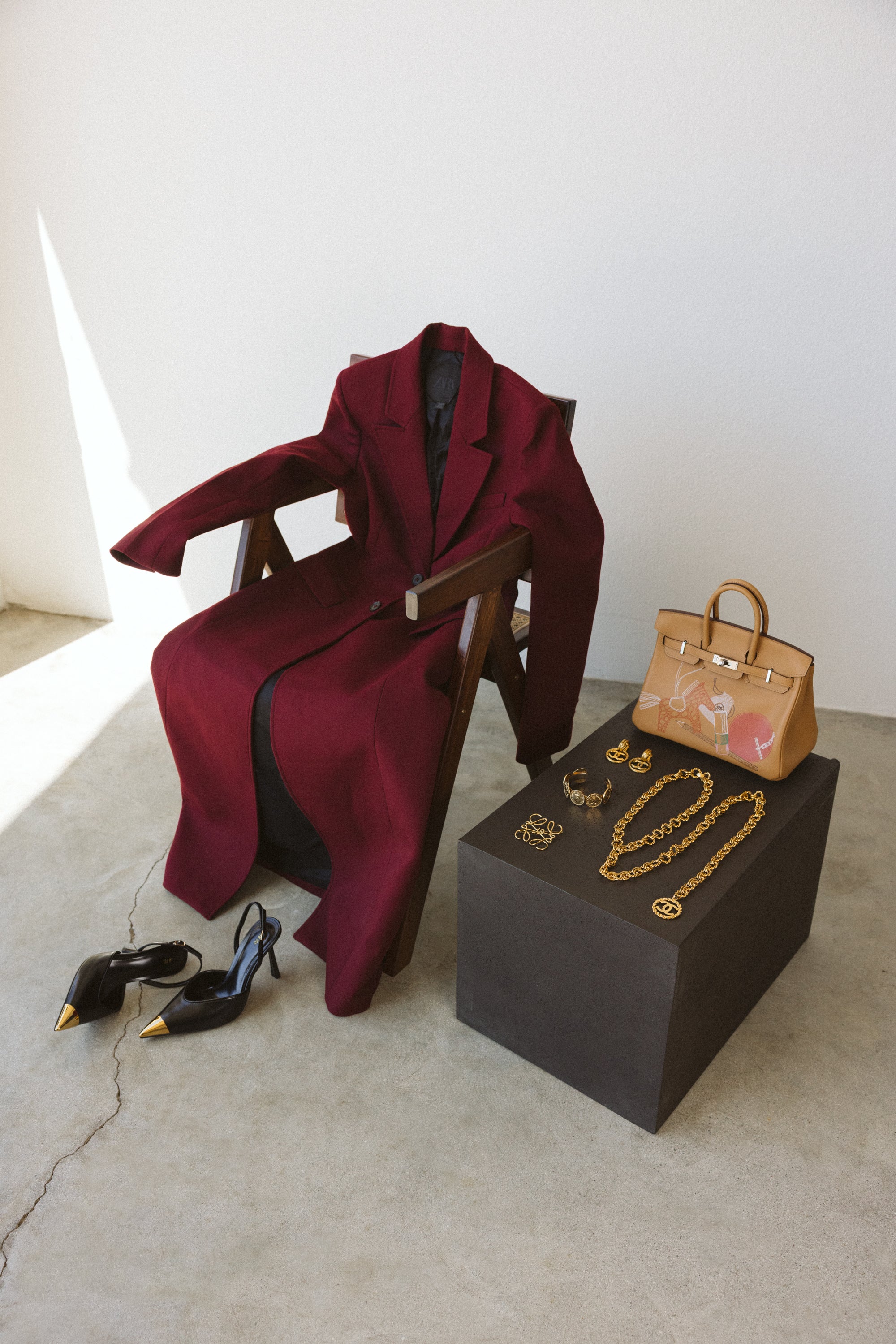 Red coat, black high heels, handbag, and jewelry on a white background