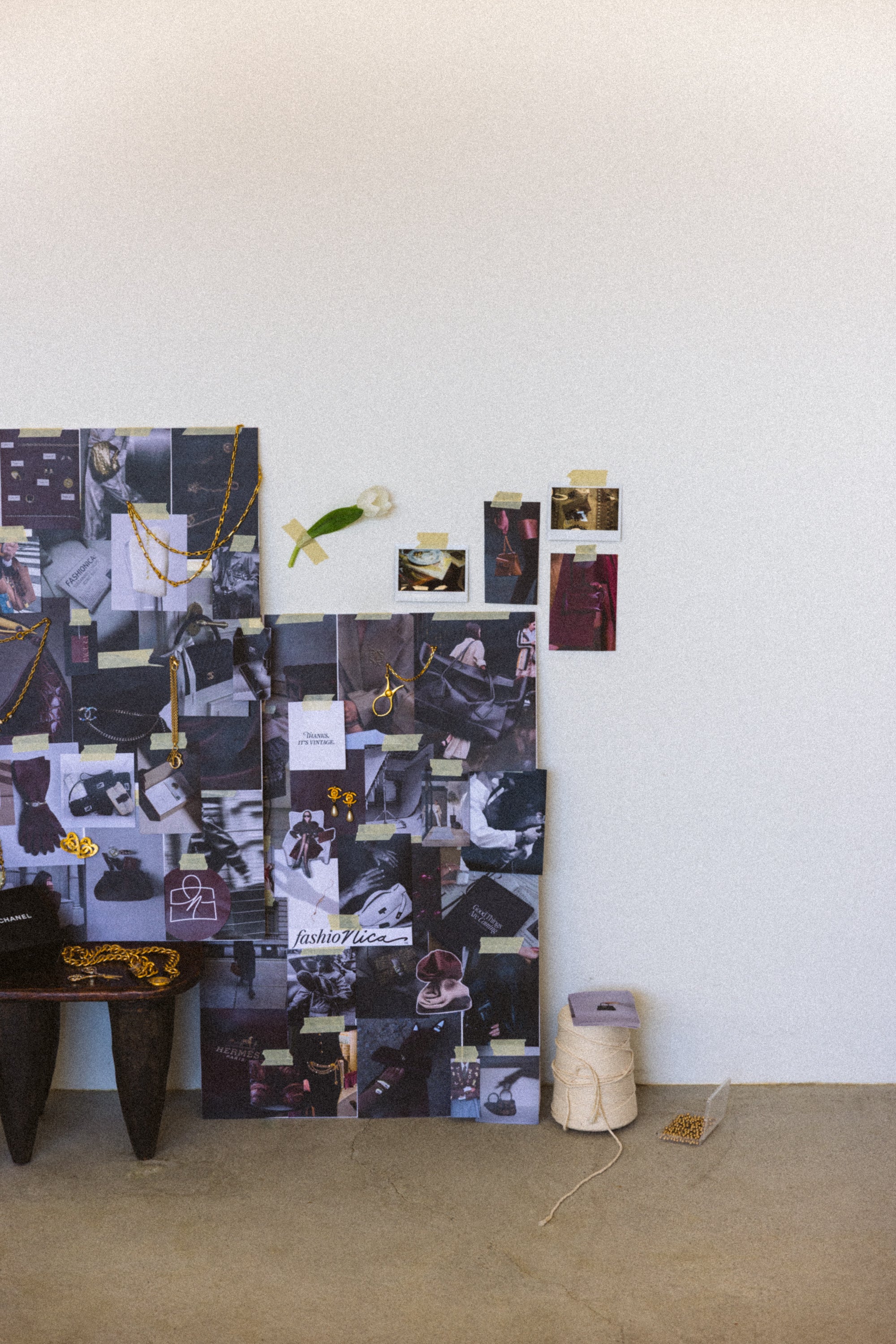 Collage of photos and notes on a wall with a small table and roll of tape in the foreground.