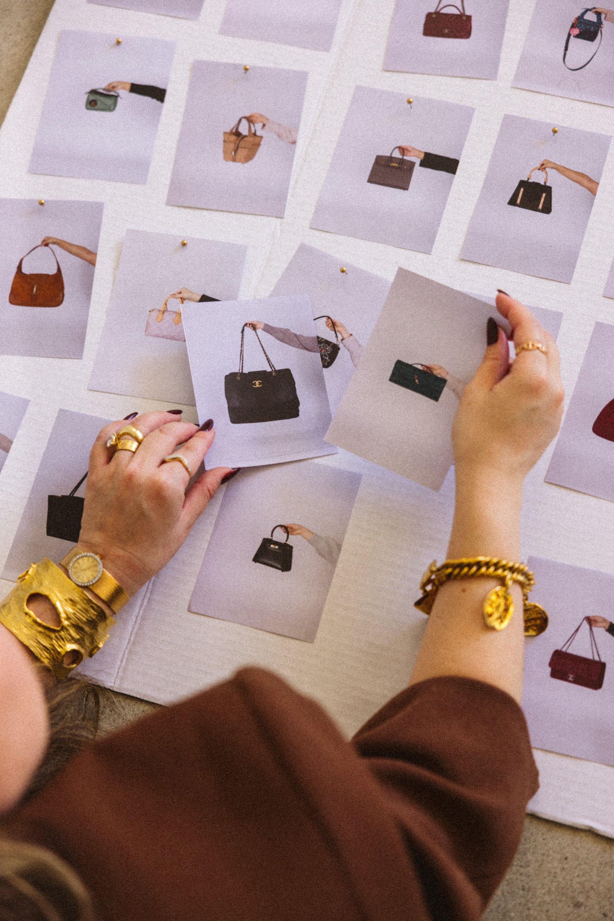 Person selecting a handbag from a grid of images on a table.