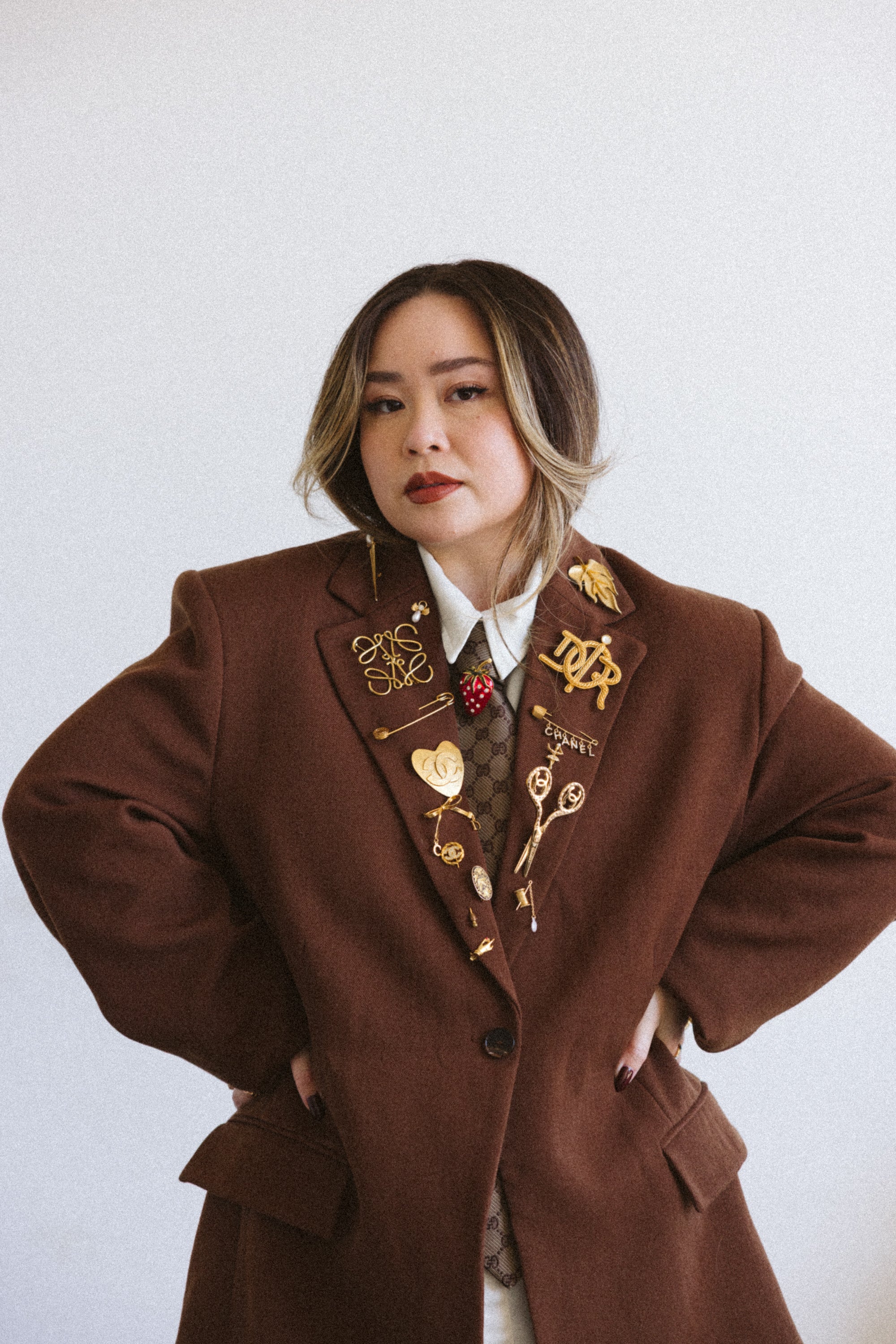 Person wearing a brown coat with decorative elements on a plain background