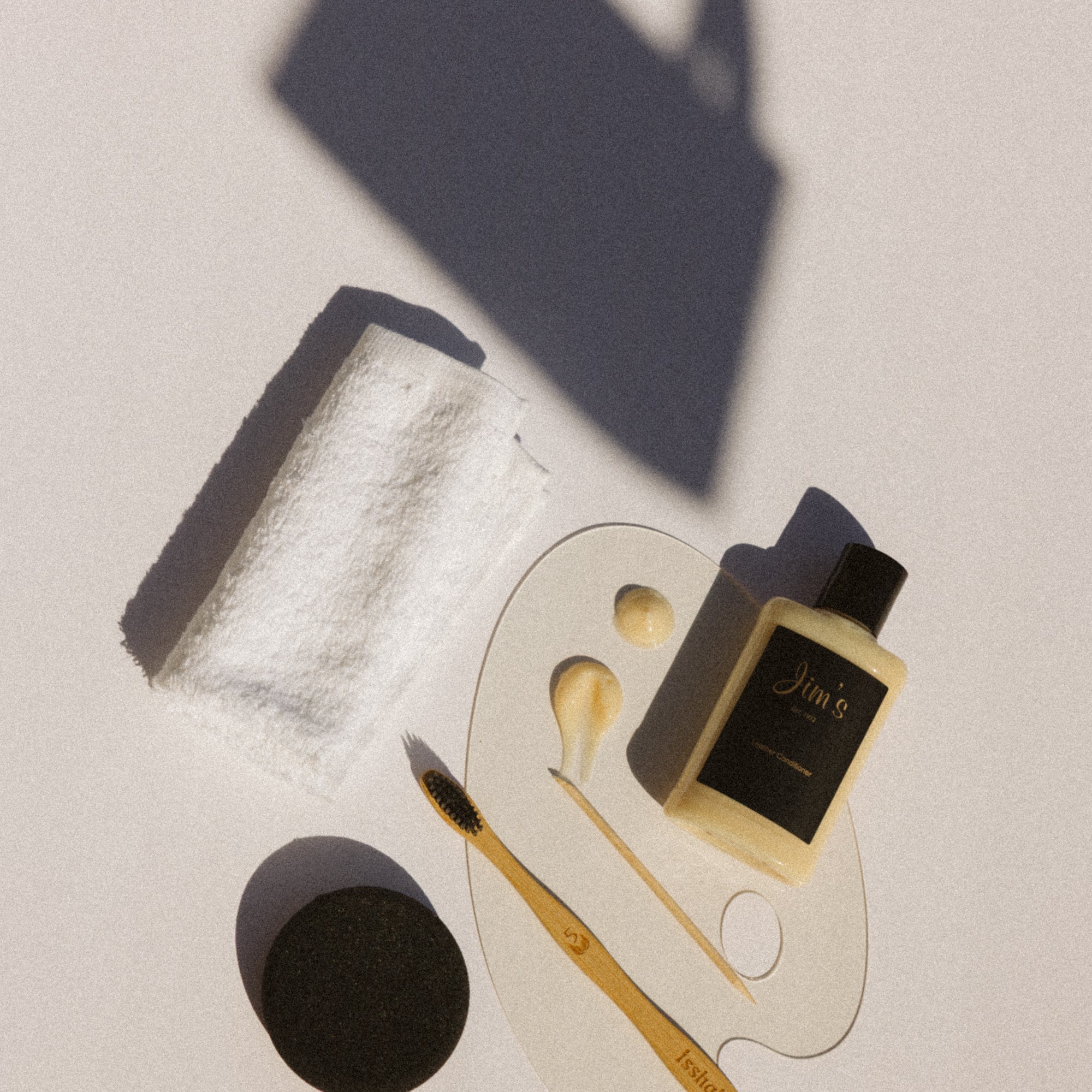 Gold and black leather cleaning tools and products on a light surface
